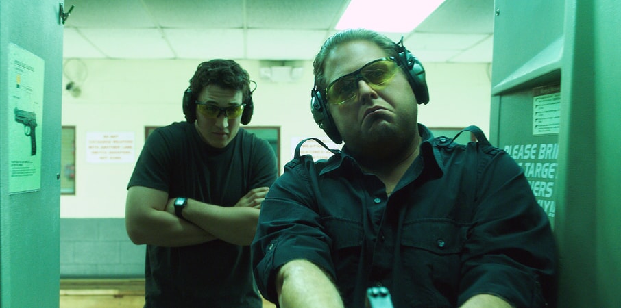 MILES TELLER as David and JONAH HILL as Efraim at indoor shooting range
