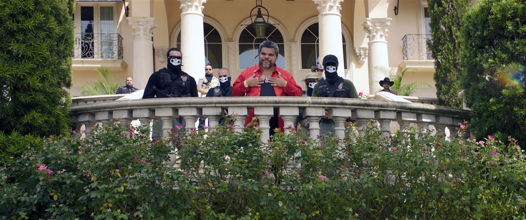 LUIS GUZMÁN as Bacon with masked men behind him