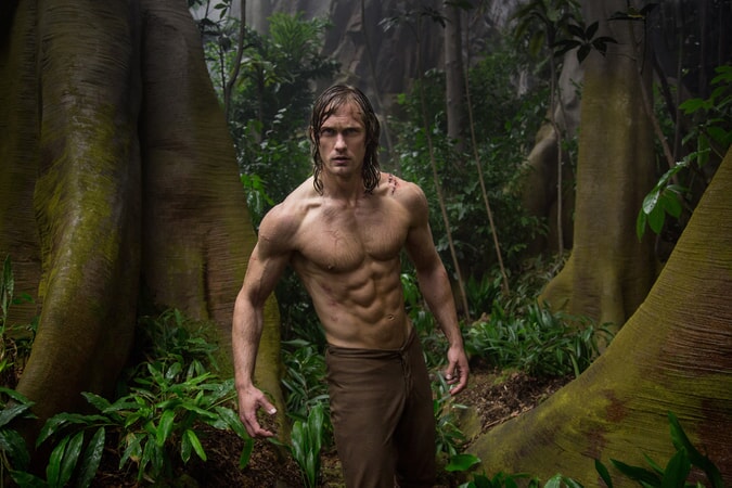 Shirtless Alexander Skarsgård as Tarzan standing in the jungle