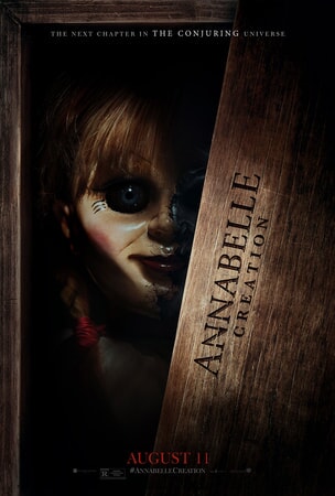 Annabelle doll peering out of a wooden box with "Annabelle Creation" stamped on it