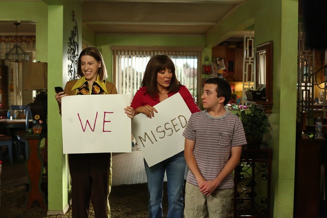 Eden Sher, Patricia Heaton and Atticus Shaffer holding cardboard signs that say "We" "Missed" in Season 9, Epsiode 1 "Vive Le Hecks"